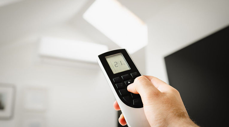 A person holding a remote control, positioned in front of a plain white ceiling.