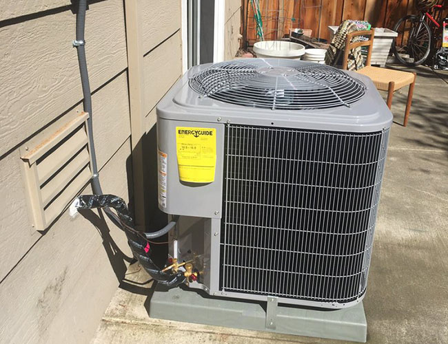 A close-up of an outdoor air conditioning unit installed beside a house, featuring visible connections and energy guide label.