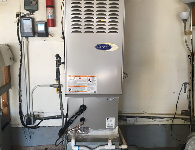 Gas furnace and water heater installed in a garage, showcasing home heating and hot water systems.
