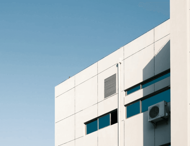 A white building featuring a window and an air conditioner mounted below it.